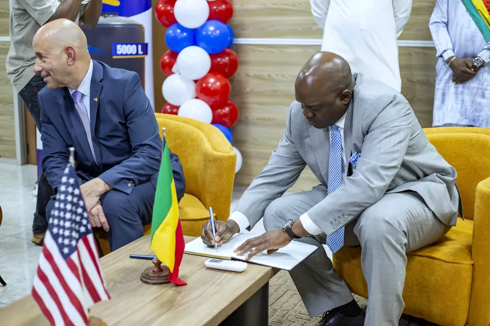 Signing the university's opening register, with the flags of Mali and the United States